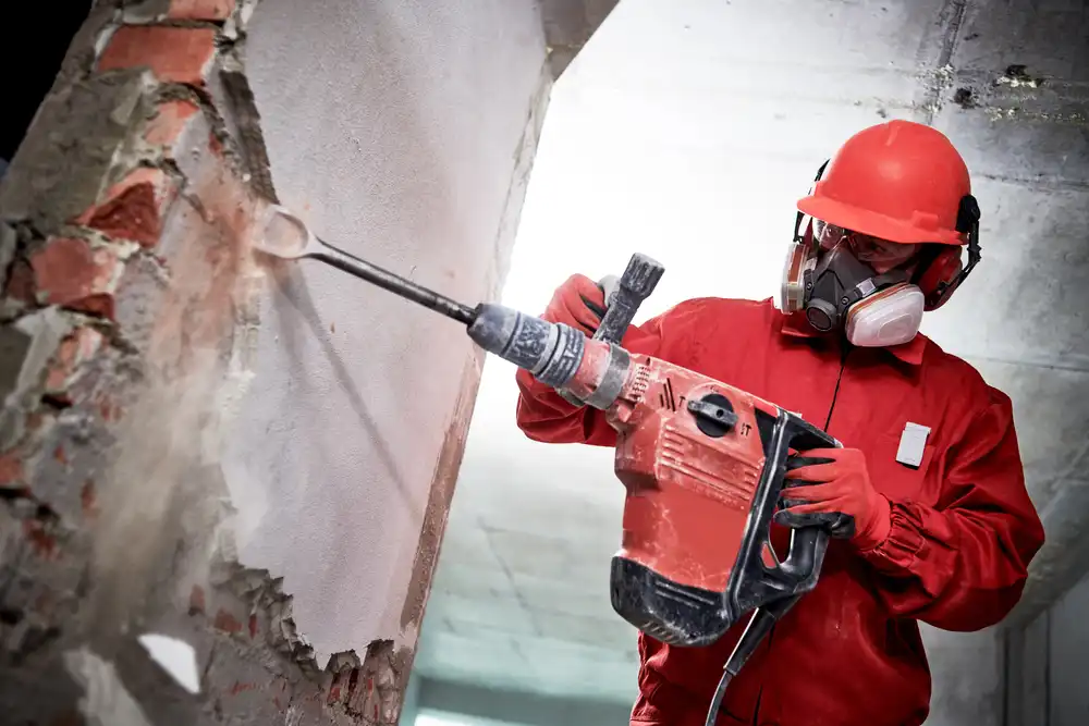 Abrissarbeiten und Entkernung – Bauarbeiter mit Abbruchhammer bei Rückbau einer Wand